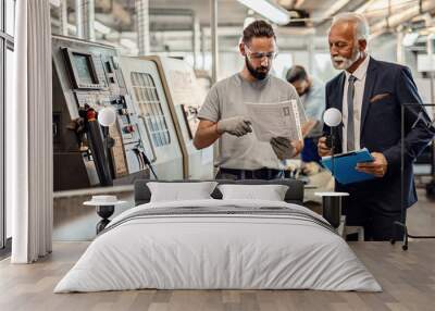 Mature company manager and worker going through reports in industrial facility. Wall mural