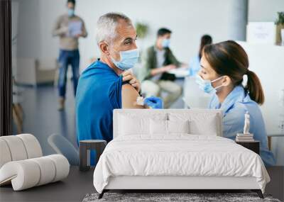 Mature man getting adhesive bandage on his shoulder after coronavirus vaccination. Wall mural