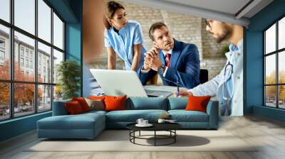 Mid adult businessman talking to a team of doctors in the office. Wall mural