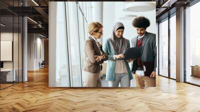 Multiracial group of business colleagues working on laptop at corporate office. Wall mural