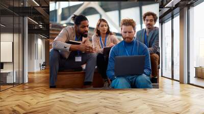 Multiracial group of business people cooperating while using laptop in conference room. Wall mural