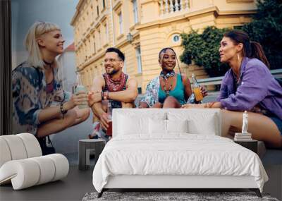 Multiracial group of happy festival goers having drink while relaxing in city. Wall mural