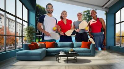 Multiracial group of happy friends playing pickleball and looking at camera. Wall mural