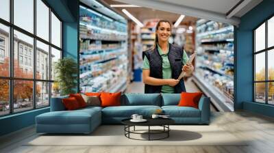 Portrait of happy female supermarket manager looking at camera. Wall mural