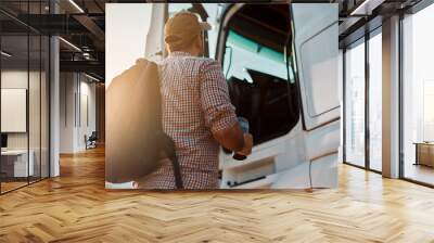 Rear view of truck driver getting into vehicle cabin. Wall mural