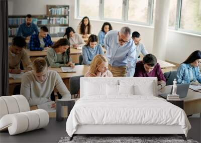 Senior teacher assists his students during a class at college classroom. Wall mural