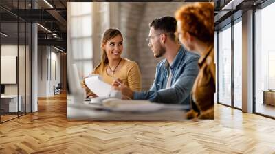 Small group of young entrepreneurs communicating in the office. Wall mural