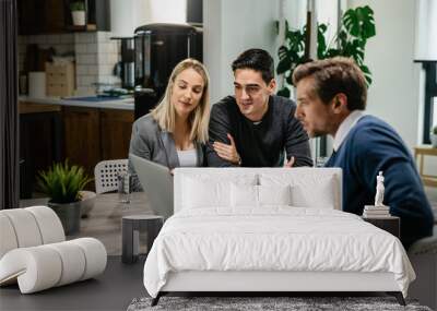 Smiling couple using a computer with their investment agent on a meeting. Wall mural