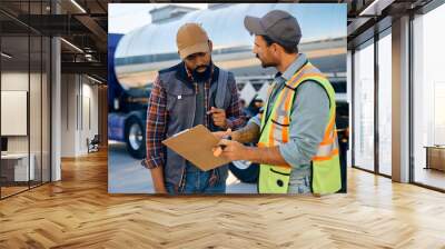 Truck dispatcher and black driver going through shipment list on parking lot. Wall mural