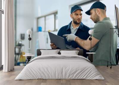 Two mechanics cooperating while working on laptop at auto repair shop. Wall mural