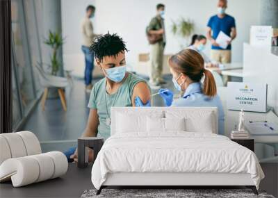 Young African American man getting vaccinated against coronavirus at vaccination center. Wall mural