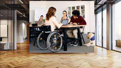 Young businesswoman talks to her colleagues while working together in office. Wall mural