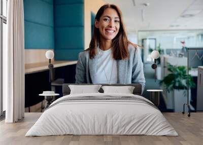 Young happy businesswoman in office looking at camera. Wall mural