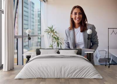 Young happy businesswoman using touchpad while working in office and looking at camera. Wall mural