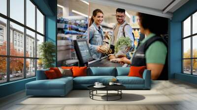 Young happy couple buying groceries in supermarket. Wall mural