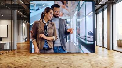 Young happy couple choosing jewelry in store at shopping mall. Wall mural