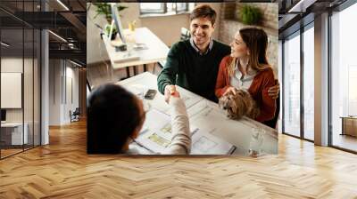 Young happy couple closing a deal with real estate agent. Wall mural