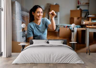 Young happy woman holds key while moving into new home. Wall mural