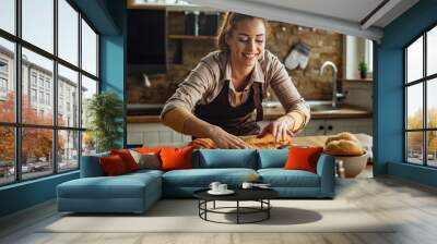 Young happy woman preparing food in the kitchen. Wall mural