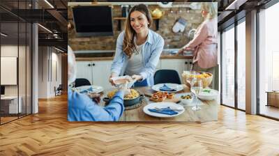 Young happy woman serving food to her father at dining table. Wall mural