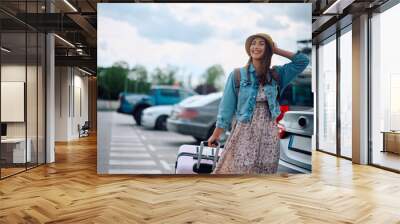 Young happy woman with suitcase going to airport terminal. Wall mural