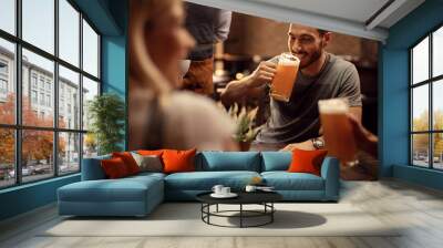 Young man drinking beer while being in a bar with his friends. Wall mural