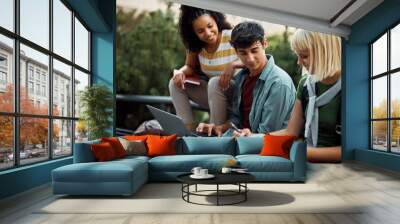 Young man using laptop while studying with female friend at campus. Wall mural