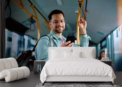 Young man using mobile phone while commuting by public transport. Wall mural