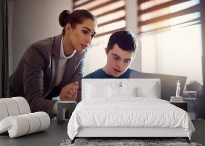 Young man with down syndrome learning to use laptop with help of his tutor at home. Wall mural