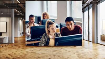 Young students cooperating while e-learning during computer class at university. Wall mural