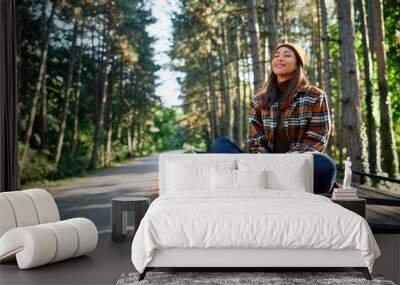 Young woman with eyes closed breathing fresh air while camping in woods. Wall mural