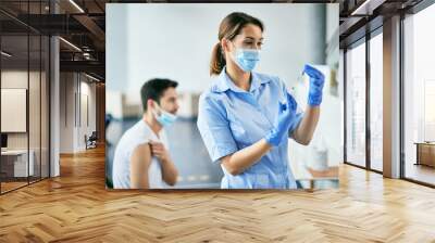 Ypung nurse preparing coronavirus vaccine during immunization at vaccination center. Wall mural