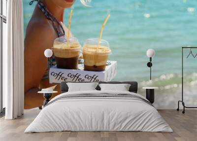 attractive female waiters holding two ice frappe coffee on the beach near sea. young woman enjoyng d Wall mural