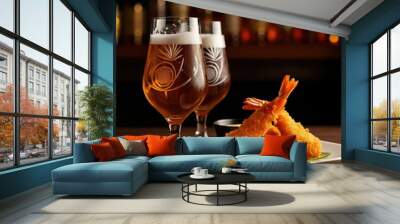 Two crystal beer glasses filled with golden lager, intricate rosette patterns etched on the glasses, a plate of breaded fried shrimp or prawns with a spicy chili sauce, blurred liquor bottles in the b Wall mural