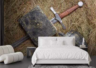 Sword, holy book and helmet on straw Wall mural