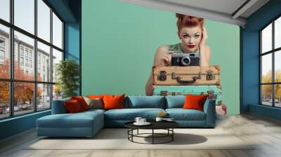 Retro woman holding a vintage camera on stacked suitcases.  Summer vacation and travel concept. Vintage style, pinup girl. Design for banner, poster, magazine with copy space Wall mural