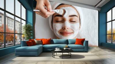 Young woman receiving facial mask in spa salon. Beauty treatment and skincare procedure concept. Wellness and relaxation. Banner, advertisement. Close-up portrait Wall mural