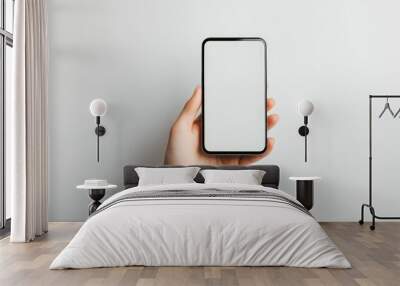 A smartphone with a white screen being held by a woman hand, contrasted against a pure white background, simple and elegant layout. Wall mural