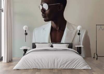 Stylish dark-skinned man poses in sunglasses and a white shirt and white jacket. Wall mural