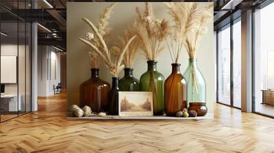 Dried autumn grasses in glass bottles on shelf Wall mural