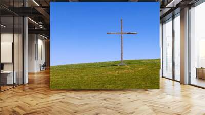 large wooden christian symbol cross standing on a grass hill or rural grassy hillside as a nature landscape religious background Wall mural