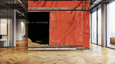 vintage retro bright red metal farm barn loading dock door open with livestock feed hay and tree shadows as agricultural architectural scene Wall mural