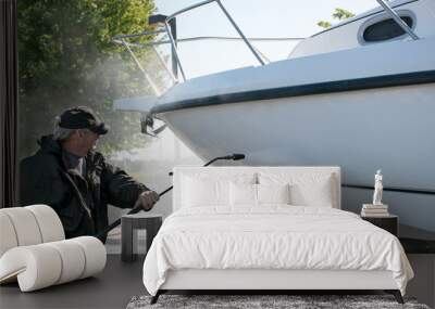 man wearing black waterproof suit while pressure washing boat hull Wall mural