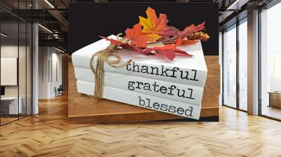 stack of books with text on white dust covers and fall leaves tied with rope string Wall mural