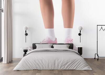 Isolated on a white background are the legs of a female wearing sneakers and socks. Wall mural