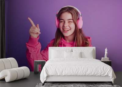 Picture a teenage student girl wearing headphones, set against a vibrant purple background, enthusiastically pointing her finger to the side with a lively and dynamic expression. Wall mural