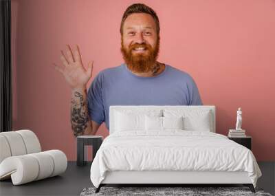 Adult handsome redhead bearded tattooed smiling happy man waving Wall mural