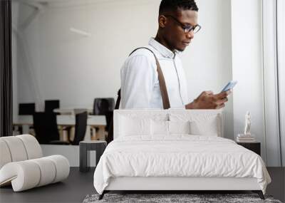 Afro american focused man in eyeglasses using mobile phone in office Wall mural