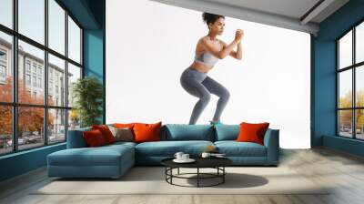 Amazing stronger sports fitness african woman make exercises isolated over white wall background. Wall mural