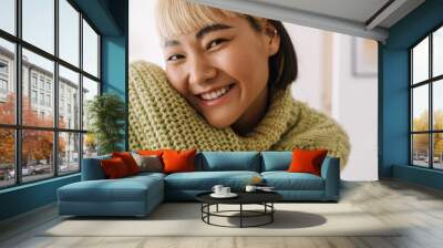 Asian girl with piercing smiling at camera while resting at home Wall mural